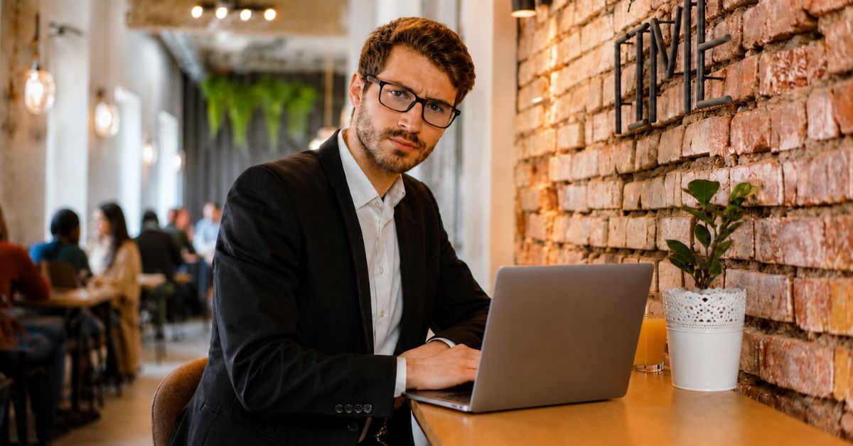 A professional man in a café setting taking notes in his planner, concentrating deeply