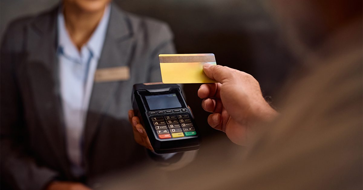 Close up of hotel guest paying with credit card at reception desk.