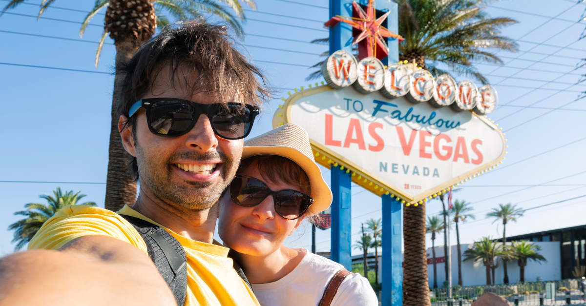 Happy young couple of tourists take selfie near Las Vegas Welcome sign
