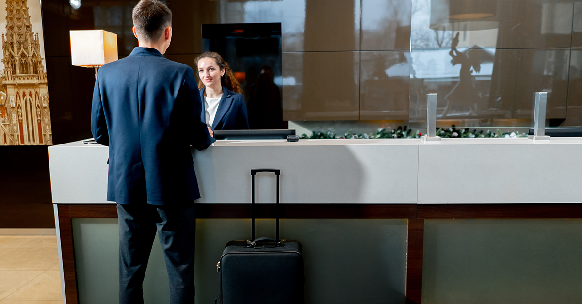 The receptionist at the counter meets the guest with luggage in hotel business travel hospitality