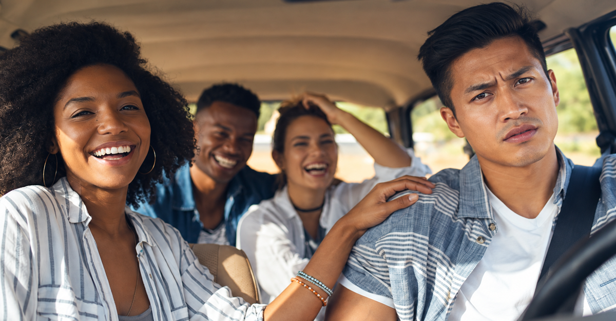 Frustrated driver sits beside three laughing passengers in car