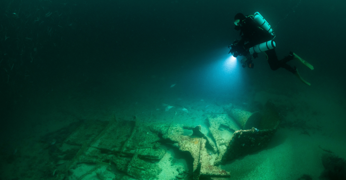 Diver equipped with a closed circuit rebreather conducts underwater photogrammetry at a wreck site.