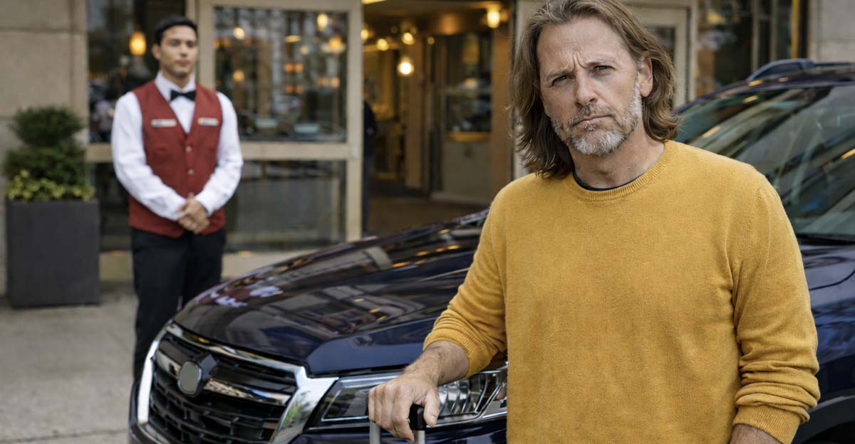 Man with damaged SUV at hotel entrance