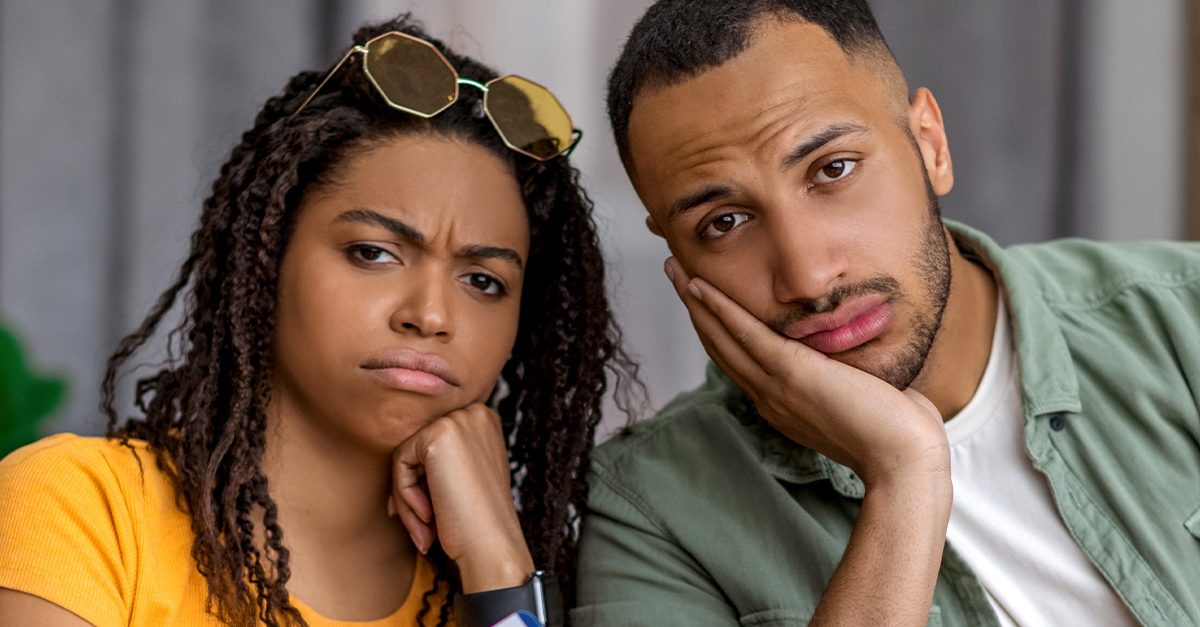 Unimpressed Black couple with yellow suitcase.