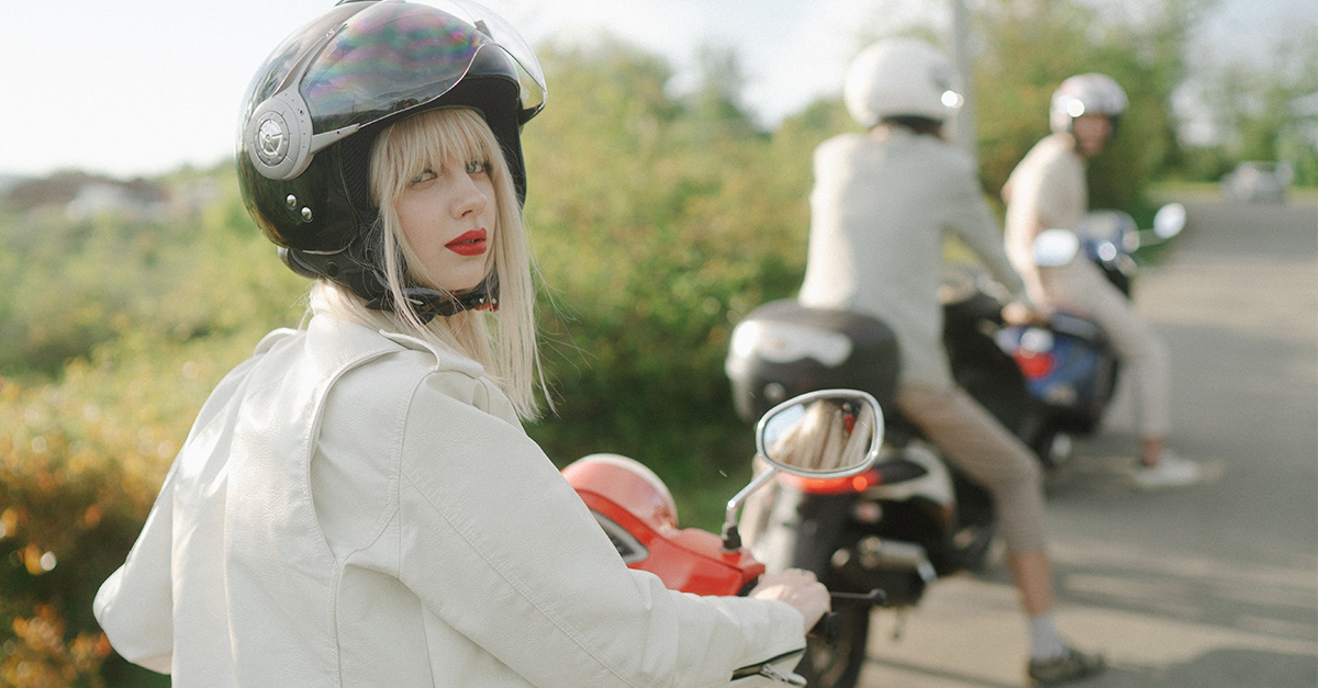 Woman on a scooter, wearing a helmet.