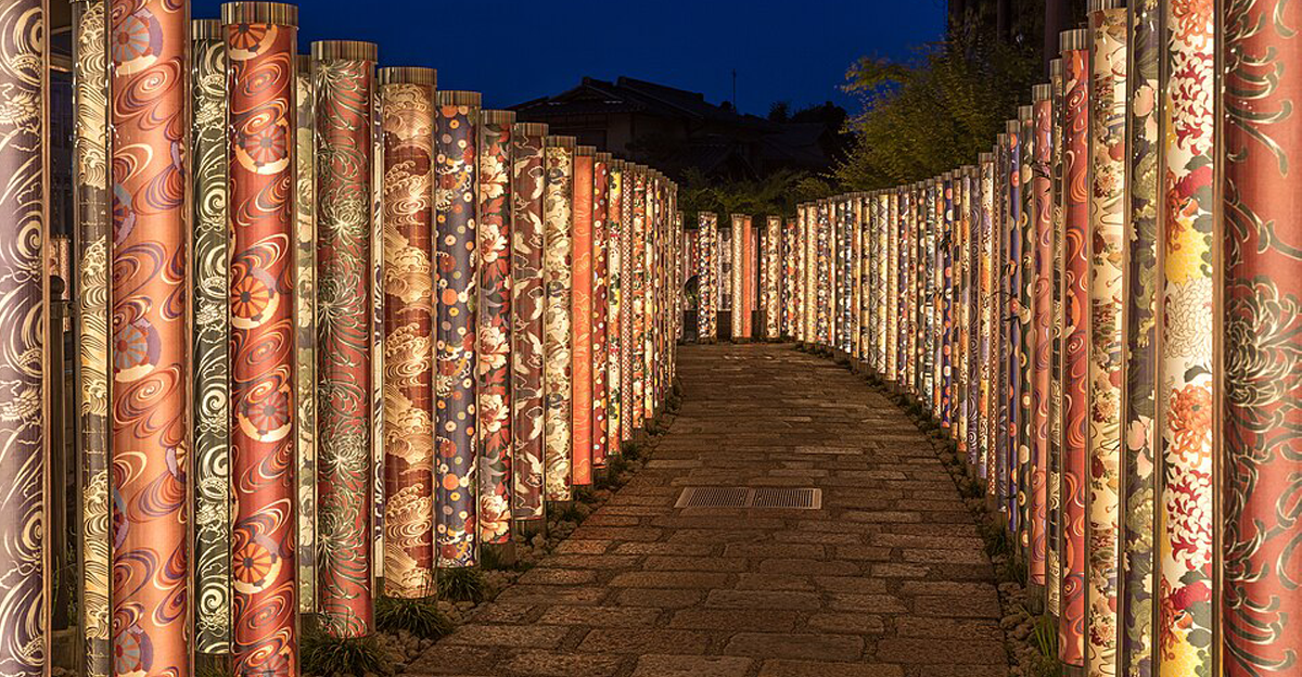 The "Kimono Forest" at night, a collection of nearly 600 kimono gowns wrapped around and sealed in poles with LED lighting inside, Arashiyama Station (Keifuku), Arashiyama, Kyoto, Japan