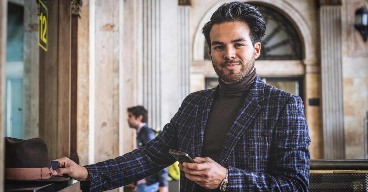Attractive confident hispanic businessman wearing casual clothes buying train ticket on train station. Blurred background