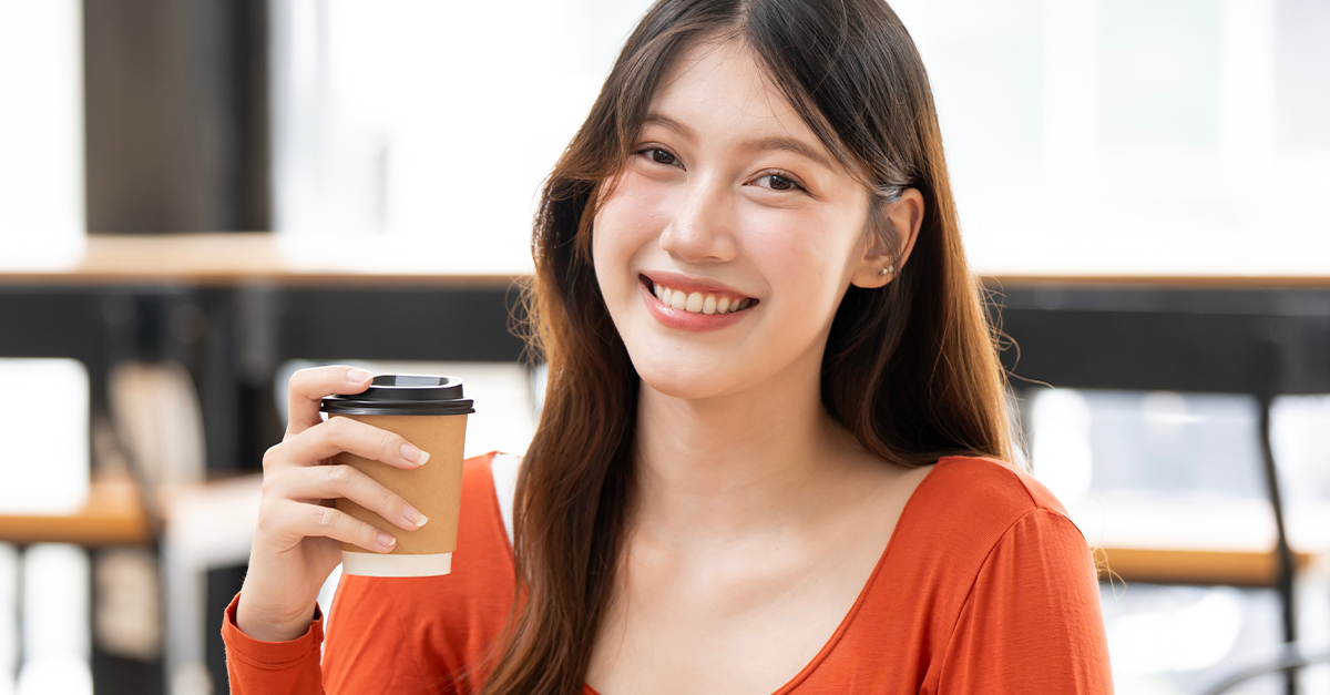 Asian woman holding a cup of coffee.
