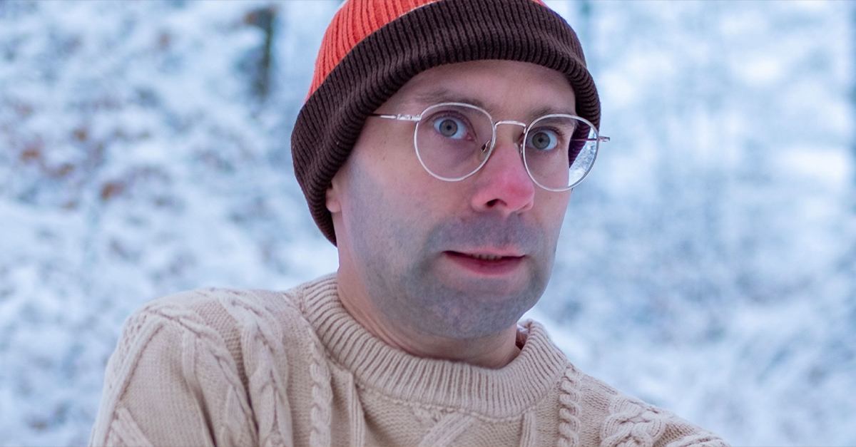 Young man in beanie and sweater, shivering in the cold.