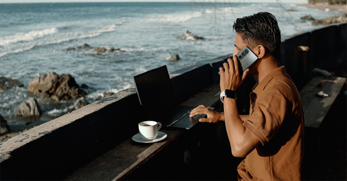 Autumn Remote Work by the Beach – Digital Nomad Using Laptop with Ocean View Under Falling Leaves”