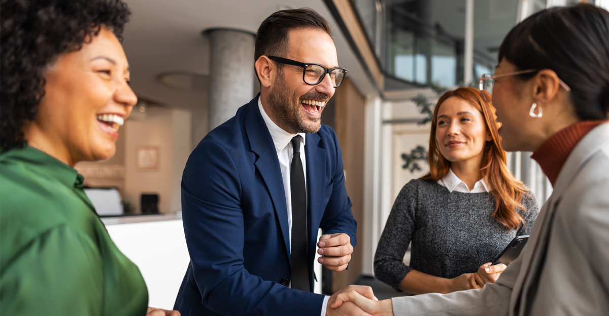 Professional office environment showcasing cheerful colleagues engaged in a friendly handshake while interacting harmoniously.