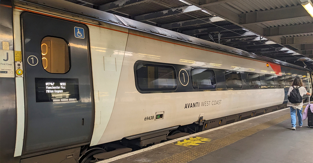 London, UK - July 26 2025: A traveler with a suitcase walks along the platform next to a modern Avanti West Coast train service departing for Manchester from Euston Station, a key transport hub