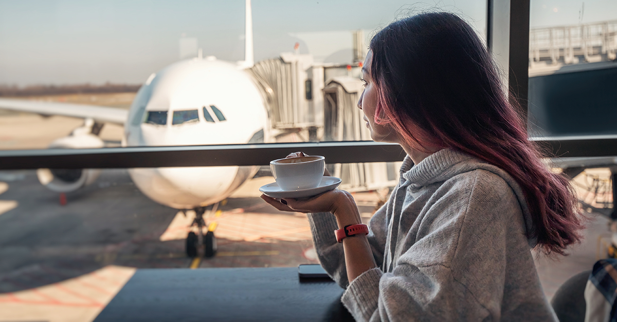 Woman drinking coffee at an airport.