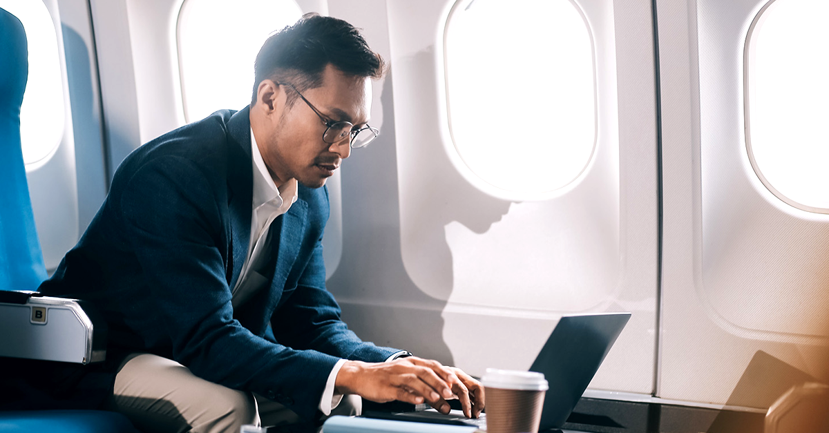 Young handsome businessman with notebook sitting inside an airplane