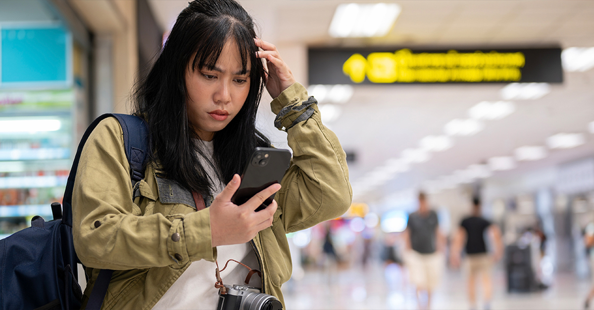 Confused woman at the airport, looking at her phone.