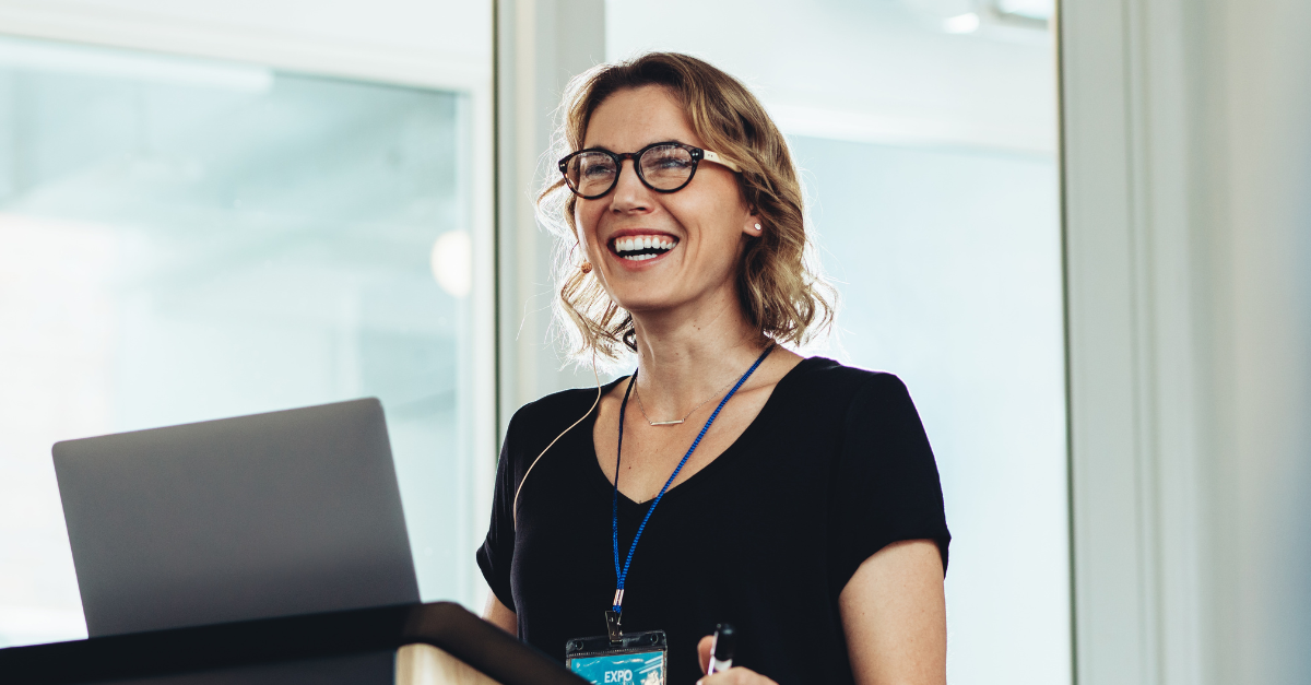 Businesswoman standing at podium with laptop giving a speech. Successful female business professional addressing a seminar.