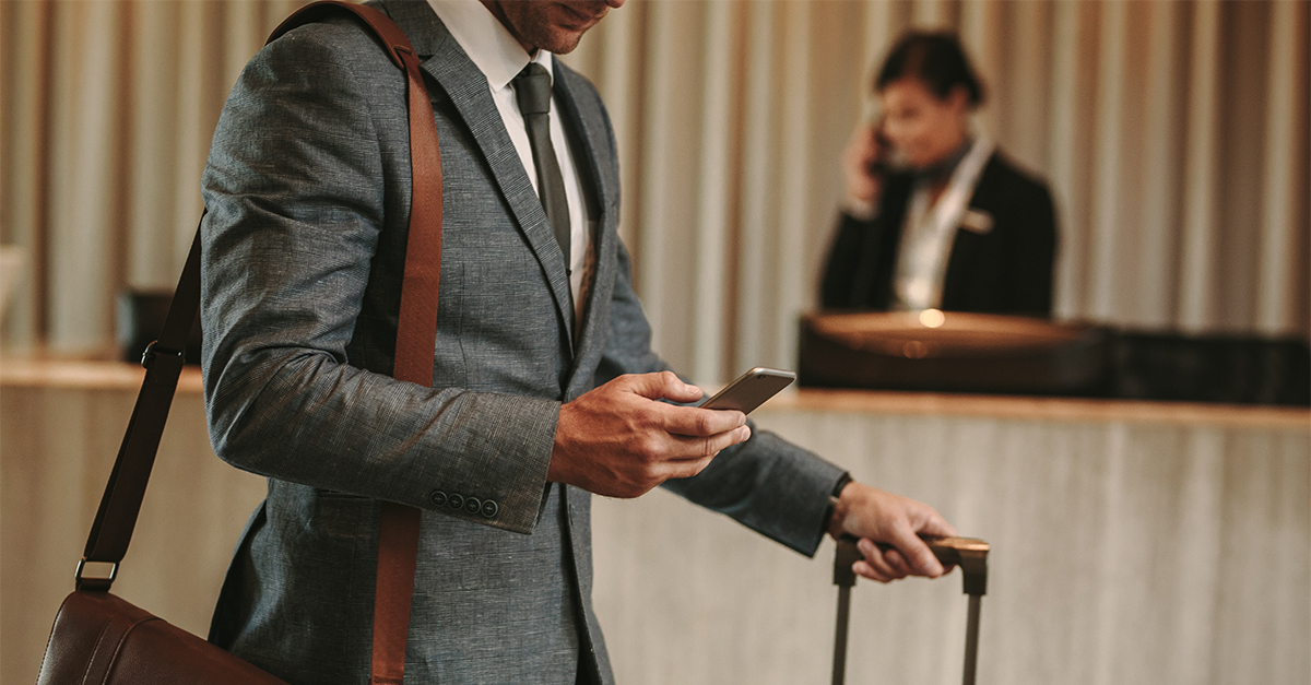 Businessman in hotel lobby with phone and luggage