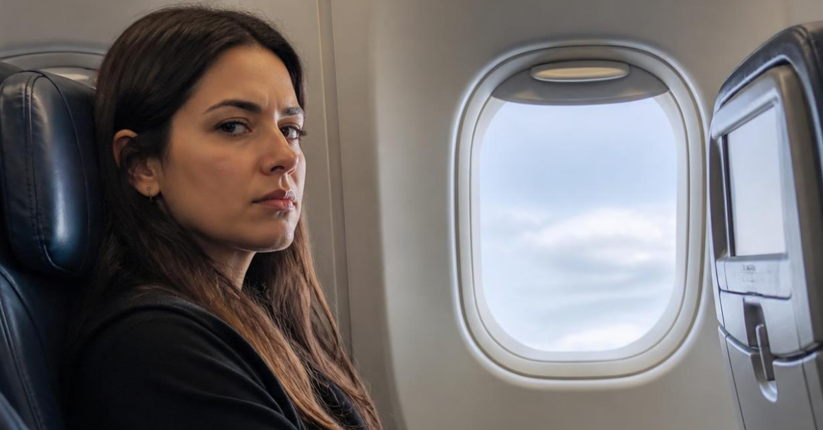 Displeased woman sitting on airplane.